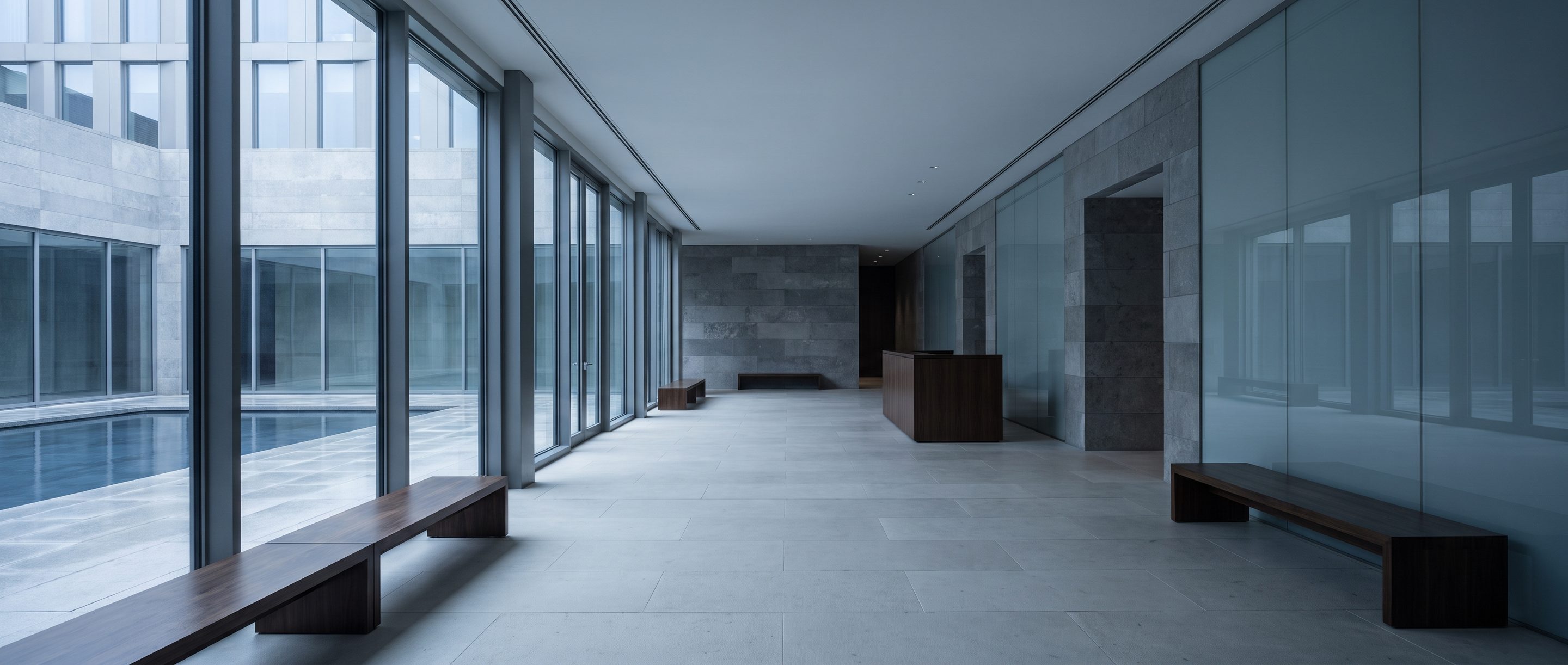 A quiet stone-and-glass office lobby, pale limestone floor.