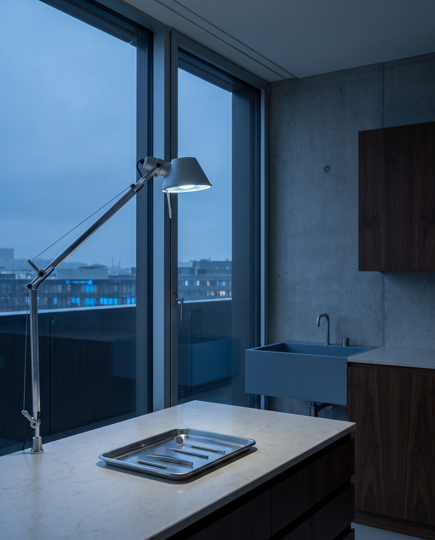 A stainless instrument tray and an adjustable lamp in an empty treatment room.