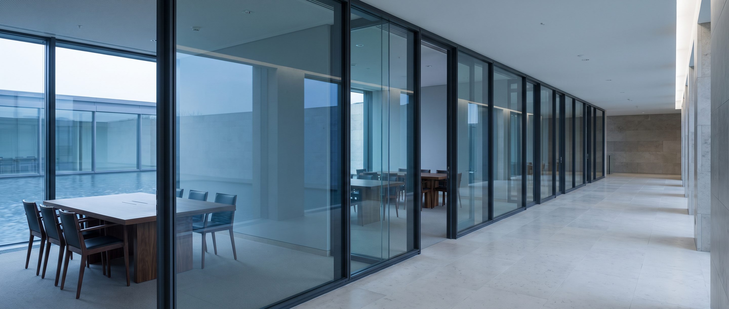 A row of glass-walled meeting rooms along a quiet corridor.