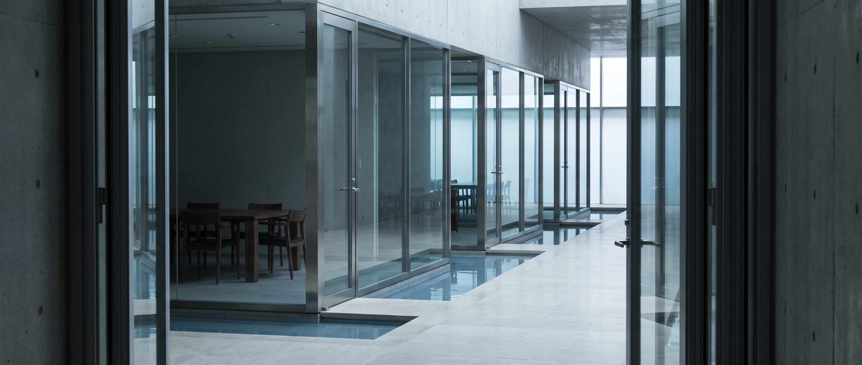 A row of glass-walled meeting rooms along a quiet corridor.