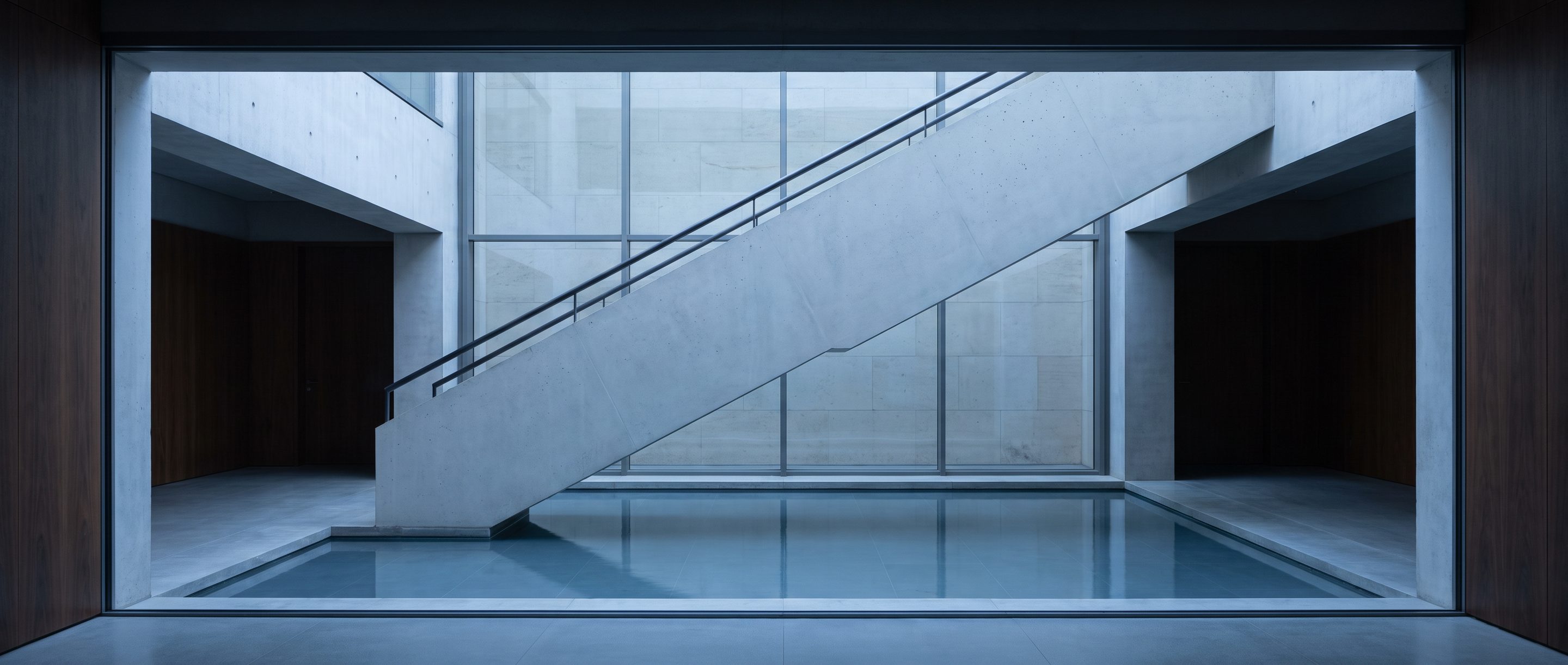 The underside of a pale concrete stair in an empty atrium.