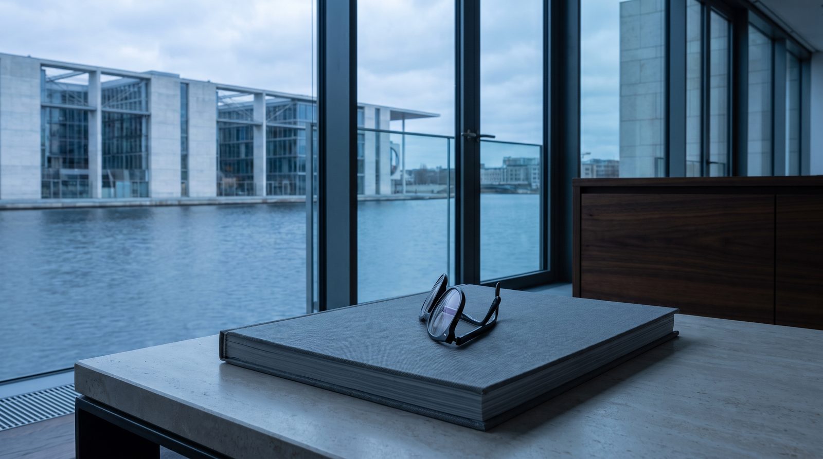 A pair of reading glasses folded on a closed report.