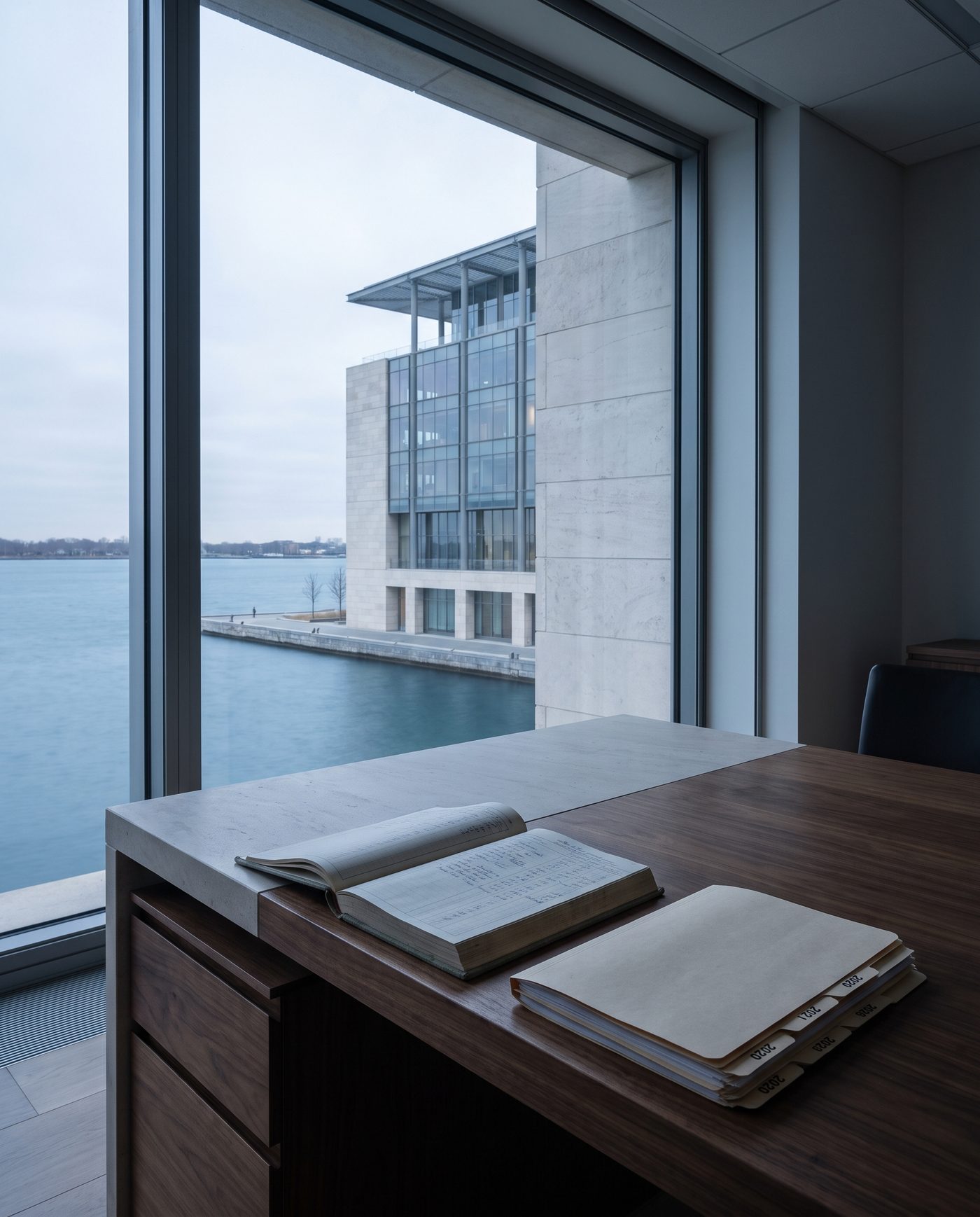 A ledger open beside a folder tabbed by year, pale desk light from the side.