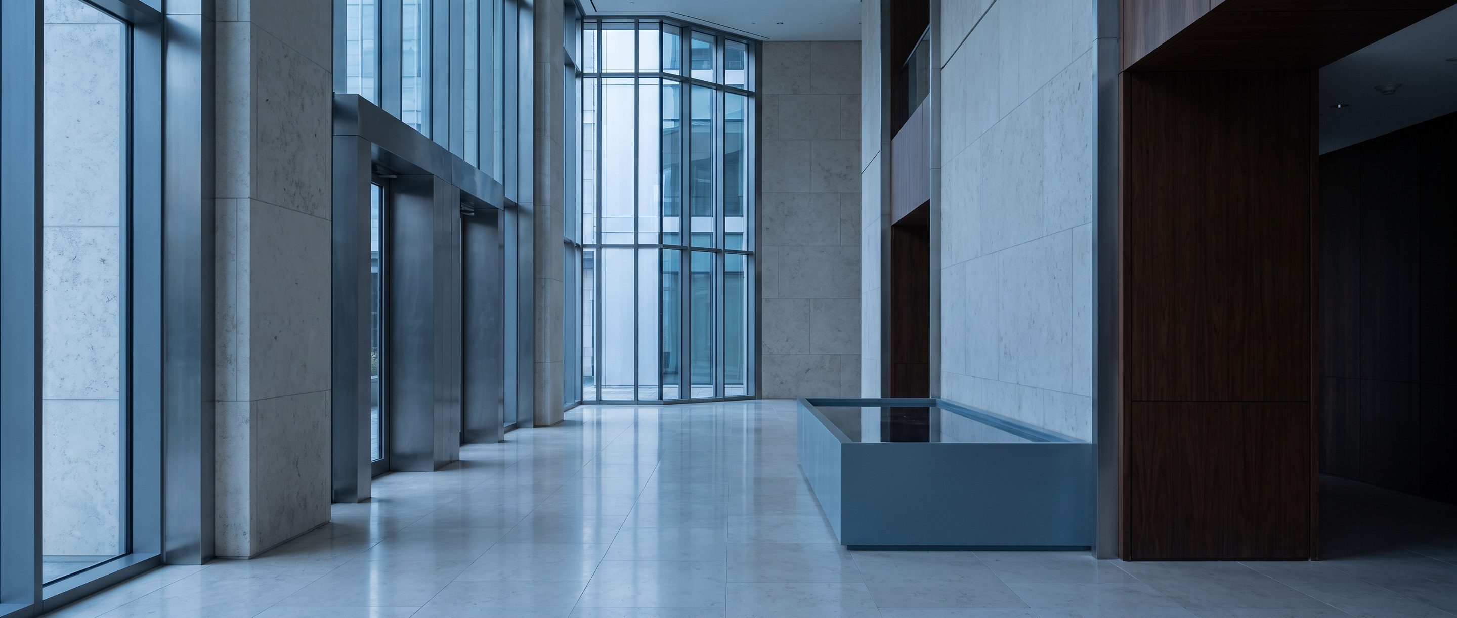 A quiet stone-and-glass office lobby, pale limestone floor.