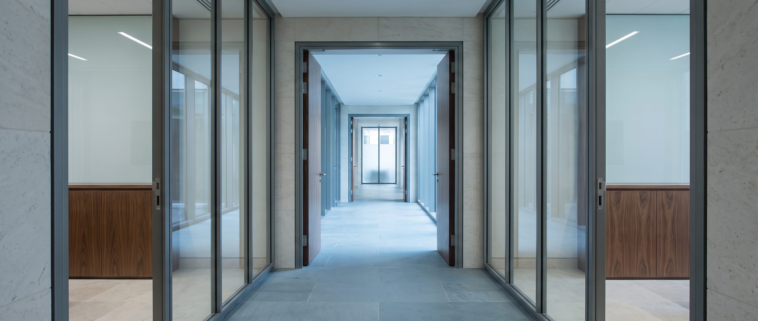 A row of glass-walled meeting rooms along a quiet corridor.